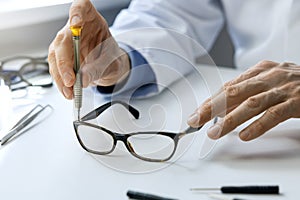 Eyewear repair service - optical technician repairing eyeglass frame with screwdriver