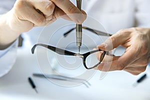 Eyewear repair service - optical technician repairing eyeglass frame with screwdriver