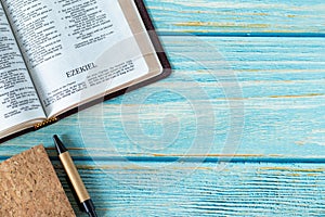 Ezekiel open Holy Bible Book on a rustic wooden background