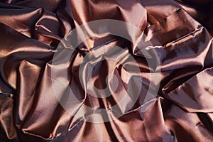 The fabric is brown with a glossy surface. a crease in the middle.