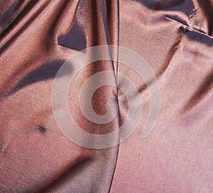 The fabric is brown with a glossy surface. a crease in the middle.