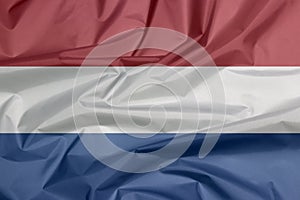 Fabric flag of Netherlands. Crease of Holland flag background.