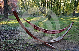 Fabric hammock net in designer hanging shape half moon crescent in park at sunrise springtime green leaves forest and red seduces