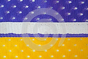 Fabric made of yellow and purple polyester background with white ribbon in the middle