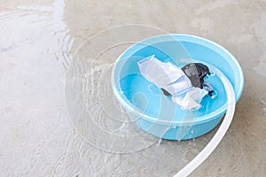 Fabric mask is soak in basin on cement floor that the water is overflowing for washing, clean and reuse to prevent the infection