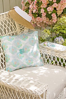Fabric pillow, needle, thread and buttons sewing notions on chair in garden. Spring and summer home decorating crafts projects photo