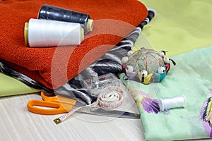 Fabric, scissors and various sewing supplies on a wooden table