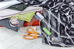 Fabric, scissors and various sewing supplies on a wooden table