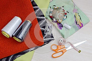 Fabric, scissors and various sewing supplies on a wooden table