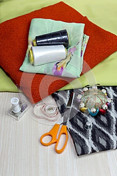 Fabric, scissors and various sewing supplies on a wooden table