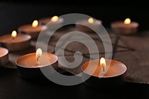 Fabric with star of David and burning candles on black background, closeup. Holocaust memory day