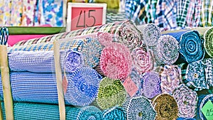 Traditional fabric store with stacks of colorful textiles, fabric rolls at market stall - textile industry background with blurred