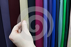 Fabric swatches in the store. The hand of caucasian woman touches the fabric