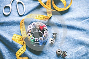 Fabric of various types and objects for sewing. Multicolored fabric, thread reels, needles, a sewing paw are needed for sewing