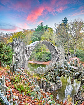 Fabulous autumn landscape in Azalea and Rhododendron Park Kromlau. Rakotz Bridge Rakotzbrucke, Devil`s Bridge