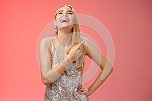 Fabulous carefree attractive blond woman in silver evening party dress laughing out loud have fun raise hand joyfully up