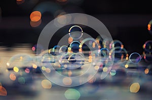 Shiny soap bubbles flying over the water and reflected in the sunset rays