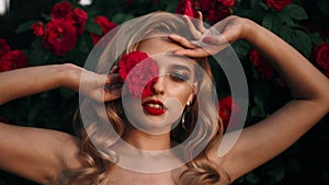 Fabulous girl with red lips in red dress on awesome summer roses background. Fantasy woman portrait. Awesome blonde