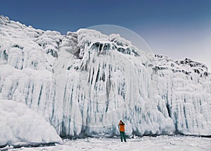 Fabulous ice icicles on the rocks of lake Baikal. Tourist photographs the icy rocks. Eastern Siberia