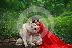 Fabulous image, dark-haired brunette attractive lady in short white dress, long red scarlet cloak lying on ground sits