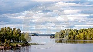 A fabulous landscape of a Finnish lake in the midst of a dense Scandinavian green forest. The concept of calm and quiet rest in