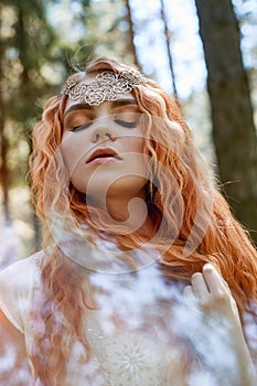 Fabulous portrait of a red-haired girl in nature with double exposure and glare. Beautiful redhead girl with long hair in forest