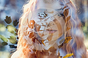 Fabulous portrait of a red-haired girl in nature with double exposure and glare. Beautiful redhead girl with long hair in forest