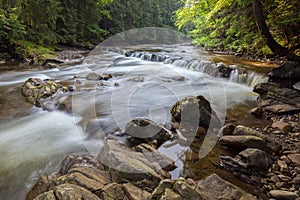 A fabulous waterfall and a raging river with crystal clear water in the Carpathians.