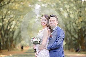 Fabulous wedding couple stands in green and yellow autumn park