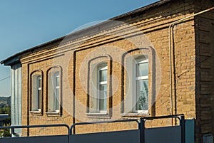 Facade of ancient brick house with new plastic windows