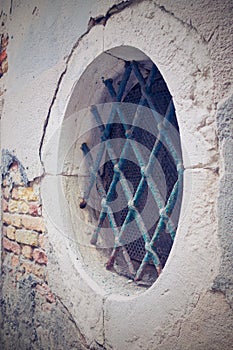 Facade ancient building with round window and a iron lattice