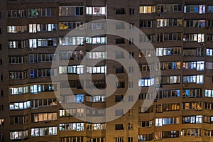 Facade of an apartment building with luminous windows at night, Ukraine