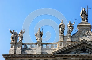 Facade of beautiful old medieval Italian Catholic Cathedral in classical style with marble statues on cruse in Rome