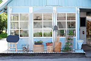 Facade blue home with garden tools, wicker basket and pots flowers. Cozy Autumn decor veranda house. Gardening concept. Cozy varan photo