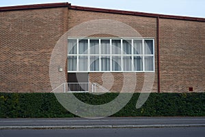 Facade of a brick building with a large window, deadpan photo
