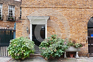 Facade of a brick wall house building with a black door in London, England