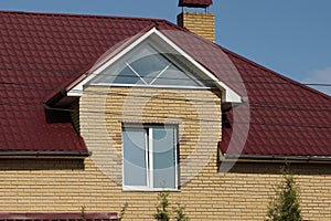 Facade of a brown brick private house with a white window