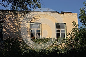 Facade of a brown old burnt house with an empty broken two windows