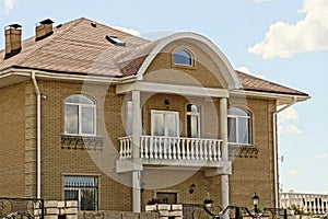 facade of a brown private brick house with a white concrete balcony