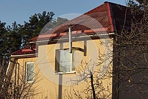 Facade of a brown private house with a white window and a metal chimney