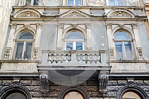 Facade of a building with ancient architecture with windows and a balcony terrace with columns, patterns and symbols on one of the