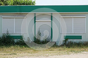 Facade of the building with windows and a door closed by white rolls on the street