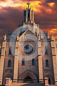 facade of the Cathedral of Sacred Heart of Jesus on background of a dramatic sky at sunset. Roman Catholic Church in