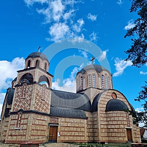 Facade of Crkva Sveta Tri Jerarha in Pozega against a blue cloudy sky