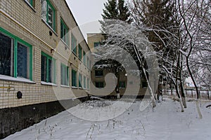 The facade of the destroyed and abandoned bakery building against the background of winter trees. The structure of the times of t