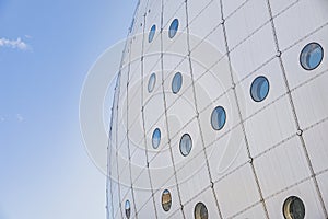 Facade detail: modern spherical building with circular windows or portholes. Quirk building architecture conveys business concept