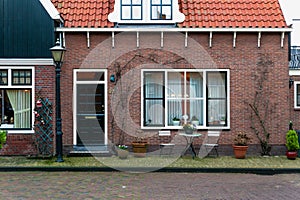 Facade of Dutch house with New Year decorations. Volendam village in Christmas. Garden furniture near a brick house in Netherlands