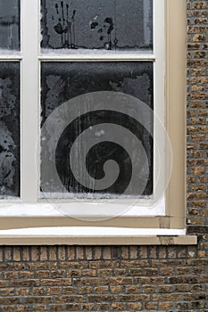 Facade of a dutch old brick house in Dordrecht, a frosty snowy dutch window in the winter, hand print, smudges and condensation on