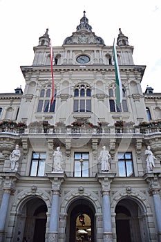 Facade with entrance, four statues, three large decorated windows, a clock, of the historic building with Baroque decorations, sea