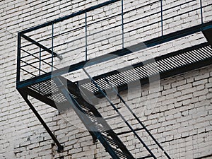 Facade with fire rescue steel ladder of old house in Moscow, Russia. Fire escape from steel metalwork on the old white brick wall